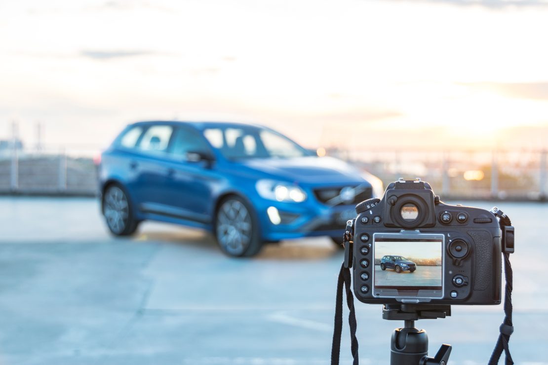 Auto dealer taking a photo of a car to showcase on lot