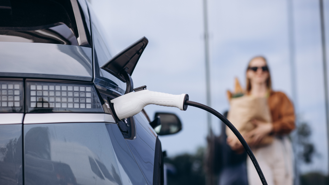 woman with groceries charging electric vehicle